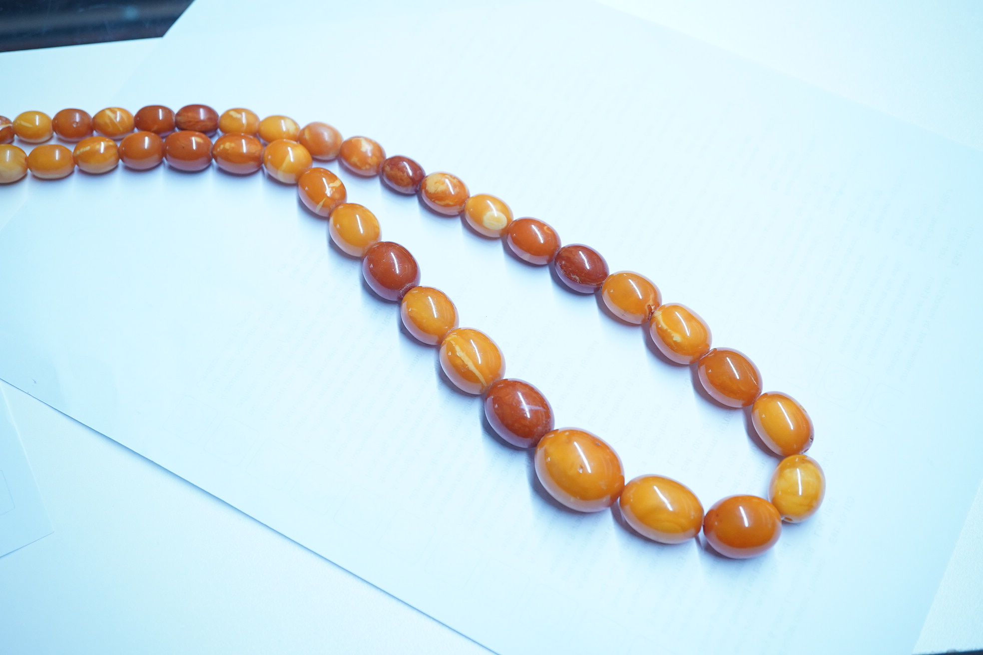 A single strand graduated oval amber bead necklace, 110cm, gross weight 103 grams. Condition - poor to fair